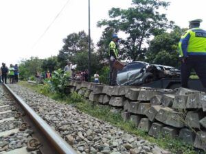 Polisi mengevakuasi mobil yang mengalami kecelakaan di perlintasan kereta api. (Foto: Rap/Tugu Jatim)
