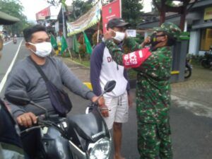 Petugas memakaikan masker kepada warga. (Foto:Dok/Tugu Jatim)