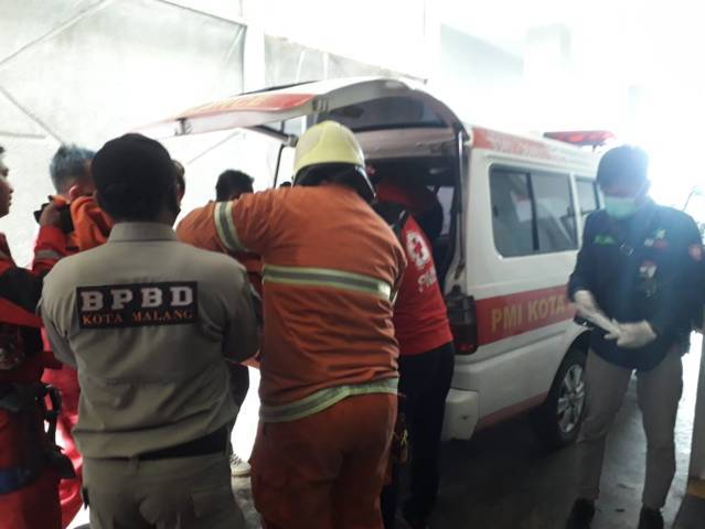 Petugas PMK, BPBD, dan TRC membawa korban ke mobil ambulans untuk dibawa ke rumah sakit. (Foto: Azmy/Tugu Jatim)