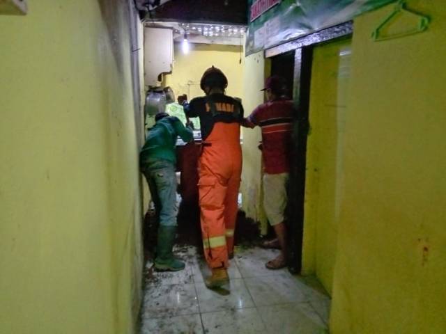 Petugas menguruk lubang rumah warga akibat tanah ambrol di Kota Batu. (Foto: Sholeh/Tugu Jatim)