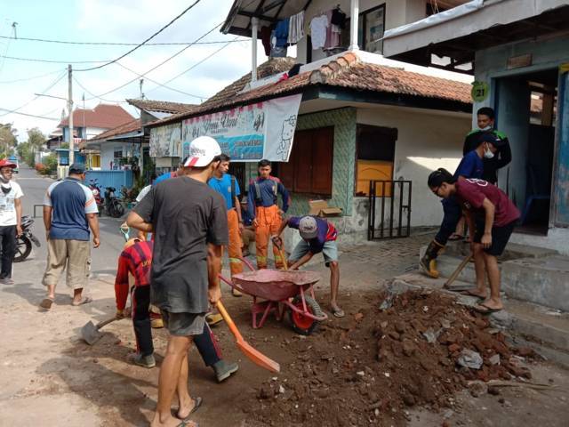 Petugas dibantu warga menguruk lubang rumah warga Kota Batu yang ambrol. (Foto: Sholeh/Tugu Jatim)