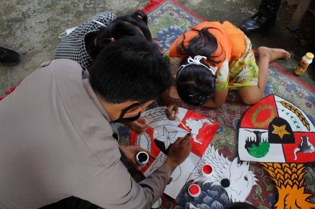 AKP Bowo Wicaksono, Kapolsek Puncu saat mendangi anak-anak untuk melukis burung garuda Pancasila. (Foto: Rino Hayyu/Tugu Jatim)