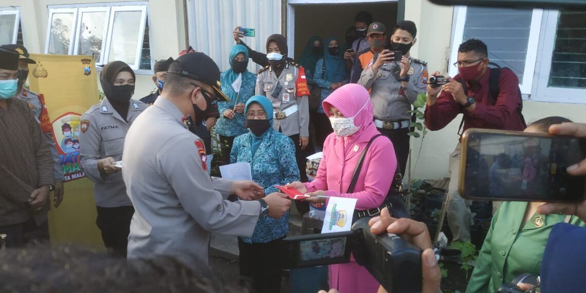 Waka Polresta Malang Kota AKBP Totok Mulyanto saat membagikan masker kepada warga Kampung Glintung, Malang, Kamis (6/8/2020). (Foto: Ulul Azmy)