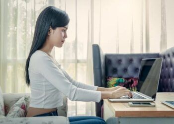 duduk dengan benar. perempuan duduk di depan laptop
