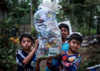 anak-anak membawa sampah. Menengok Gubuk Baca Lereng Busu: Kala Sekolah Cukup Dibayar dengan Sampah