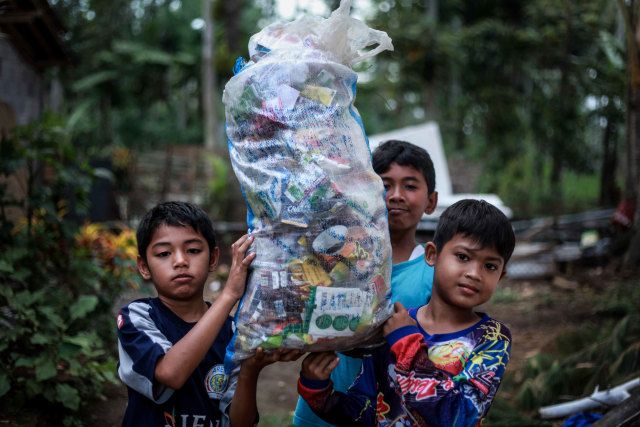 anak-anak membawa sampah. Menengok Gubuk Baca Lereng Busu: Kala Sekolah Cukup Dibayar dengan Sampah