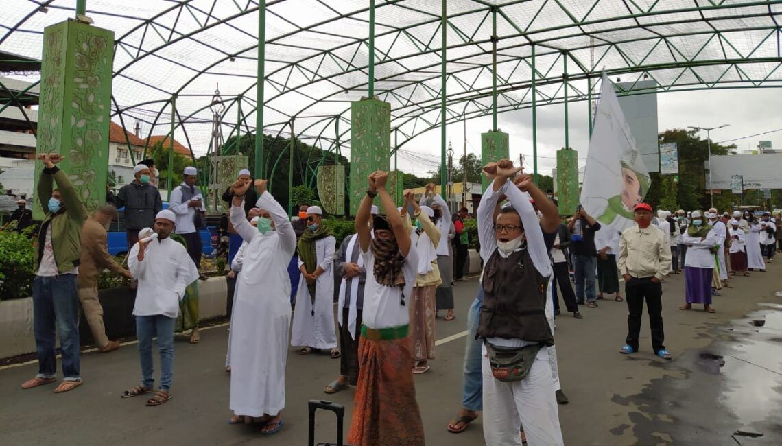 Massa aksi Muslim Malang Bersatu mengepalkan tangan terborgol sebagai aksi solidaritas menuntut pembebasan Habib Rizieq, Jumat (18/12). (Foto: Azm/Tugu Malang/Tugu Jatim)