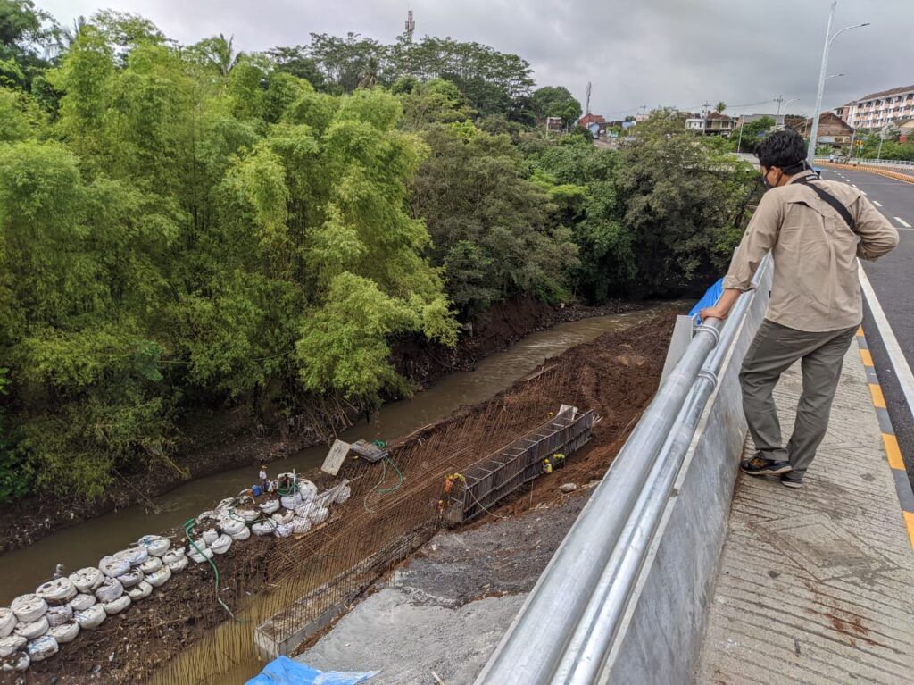 Pengerjaan bagian plengsengan di bawah Jembatan Kedungkandang masih dalam tahap pengerjaan pasca ambrol beberapa waktu lalu. (Foto: Azmy/Tugu Malang/Tugu Jatim)