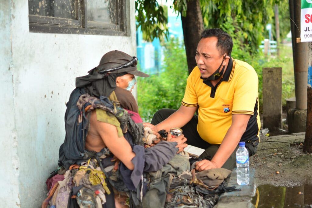 Aipda Purnomo membujuk ODGJ di Lamongan agar mau pakaiannya yang terbuat dari puluhan potongan kain itu diganti. (Foto: Dok Aipda Purnomo/Mila Arinda/Tugu Jatim)