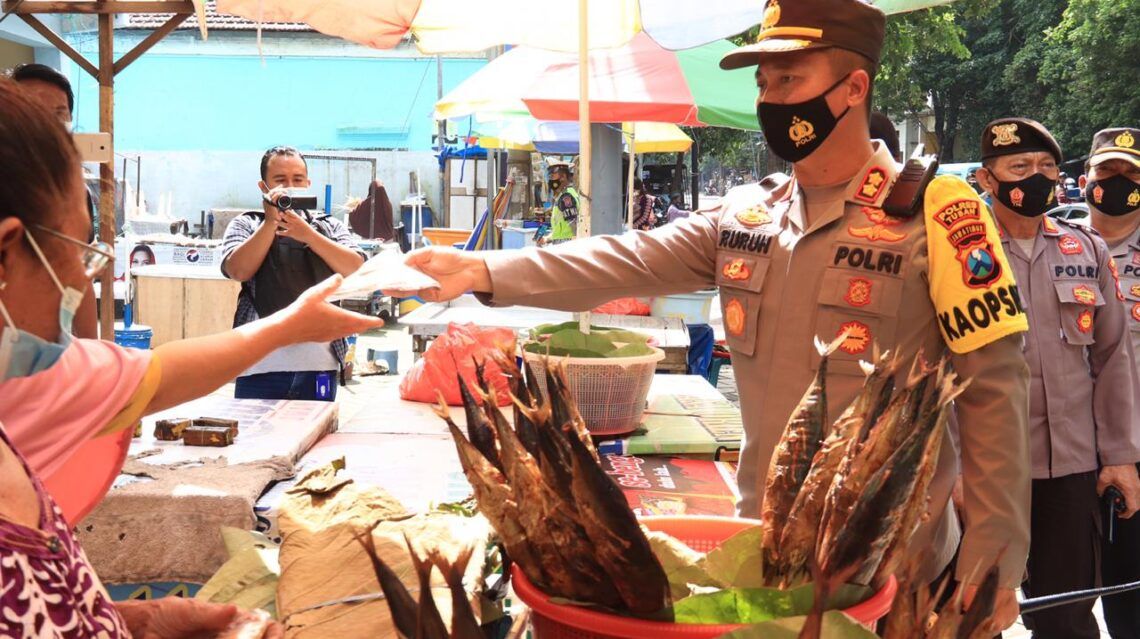 Kapolres Tuban AKBP Ruruh Wicaksono membagikan masker kepada masyarakat yang tidak mengikuti protokol kesehatan agar virus Covid-19 tak semakin menyebar. (Foto: Rochim/Tugu Jatim)