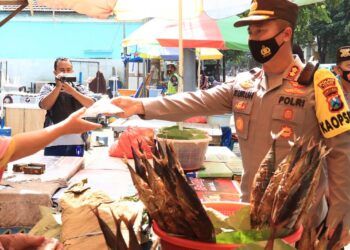 Kapolres Tuban AKBP Ruruh Wicaksono membagikan masker kepada masyarakat yang tidak mengikuti protokol kesehatan agar virus Covid-19 tak semakin menyebar. (Foto: Rochim/Tugu Jatim)