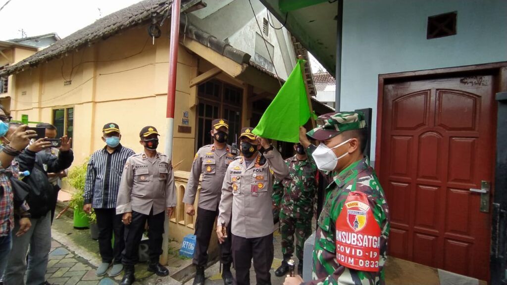 Kapolresta Malang Kota Kombes Pol Leonardus Simarmata menunjukkan bendera zonasi hijau di RW 1, Kelurahan Sukoharjo, Klojen, Kota Malang, Sabtu (13/02/2021). (Foto: Azmy/Tugu Jatim)