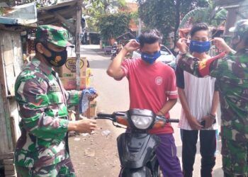 Anggota TNI dari Koramil Kraton Kodim 0819 Pasuruan bagikan masker ke masyrakat. (Foto: Dokumen)