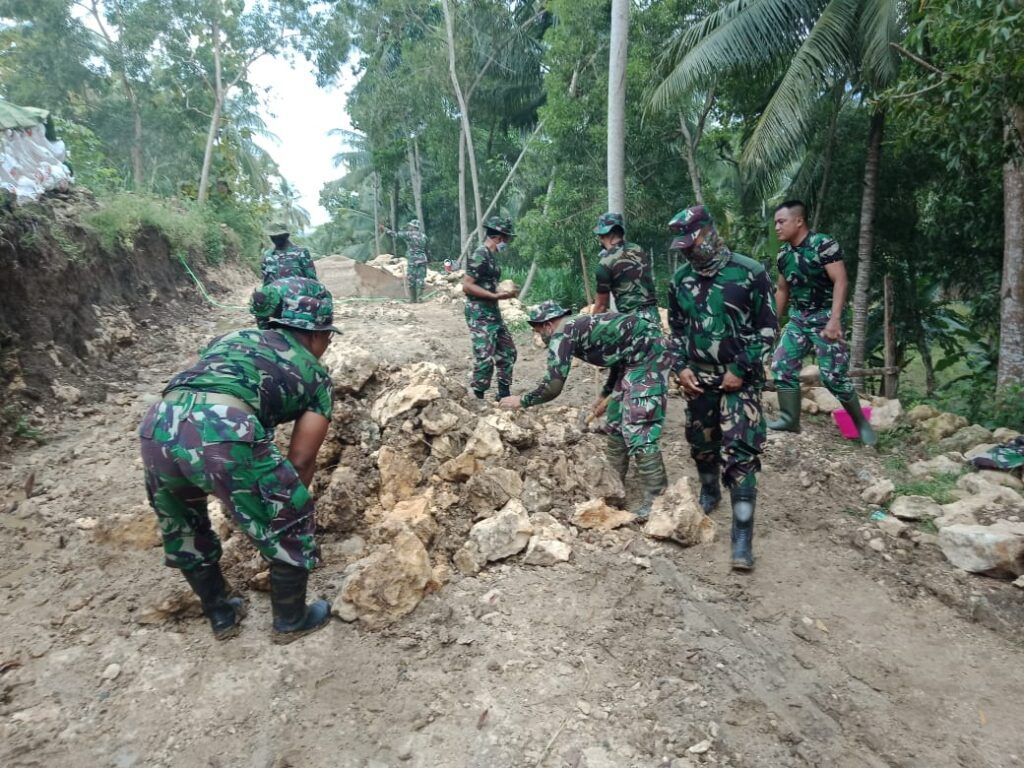 Anggota TNI dari Kodim 0801/Pacitan Jawa Timur yang turun membantu membangun jalan desa di Desa Widoro, Kecamatan Donorojo, Kabupaten Pacitan, Rabu (10/2/2021). (Foto: Dokumen/Kodim 0801 Pacitan) tugu jatim