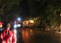 Petugas membersihkan material longsor di jalur kawasan Payung Kota Batu dengan alat berat, Sabtu (27/2/2021). (Foto : Pusdalops BPBD Kota Batu) tanah longsor, jalur malang-kediri, tugu jatim