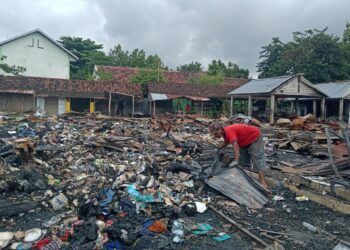 Fais, tukang rongsok yang mengambil seng bekas atap pasar yang dijual kepadanya. (Foto : Mila Arinda/Tugu Jatim)