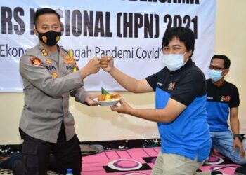 Ketua PWI Tuban, Pipiet Wibawanto saat memotong tumpeng dan diserahkan ke Kapolres Tuban, AKBP Ruruh Wicaksono. (Foto: Moch Abdurrochim/Tugu Jatim)