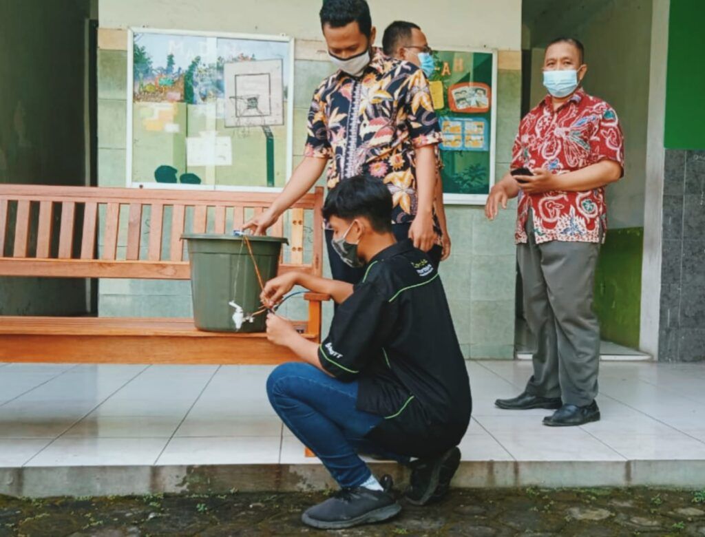 Ibrahim Khalilullah (siswa yang memakai baju hitam) dan Khoirul Muhlisin (siswa yang memakai baju motif kotak-kotak) sedang mencoba alat cuci tangan sensor. (Rangga Aji/Tugu Jatim) SMK YPM 11 Wonoayu, alat cuci tangan otomatis sensor elektronik