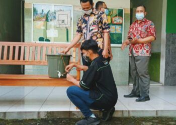 Ibrahim Khalilullah (siswa yang memakai baju hitam) dan Khoirul Muhlisin (siswa yang memakai baju motif kotak-kotak) sedang mencoba alat cuci tangan sensor. (Rangga Aji/Tugu Jatim) SMK YPM 11 Wonoayu, alat cuci tangan otomatis sensor elektronik