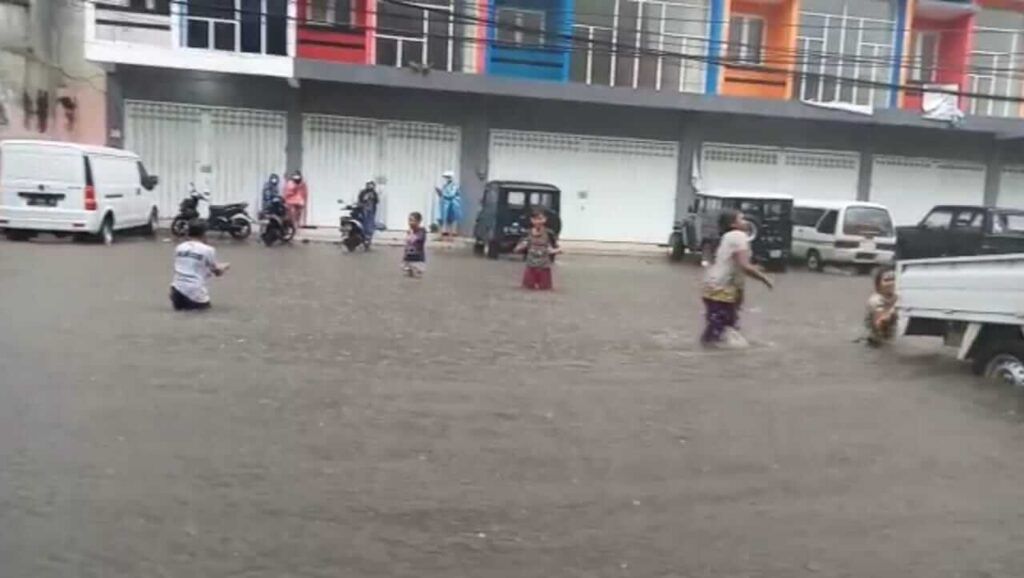 Anak-anak memanfaatkan banjir di kawasan Jalan Kedawung, Kota Malang, dengan berenang secara gratis Senin (22/03/2021). (Foto: Azmy/Tugu Jatim)