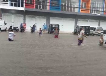 Anak-anak memanfaatkan banjir di kawasan Jalan Kedawung, Kota Malang, dengan berenang secara gratis Senin (22/03/2021). (Foto: Azmy/Tugu Jatim)