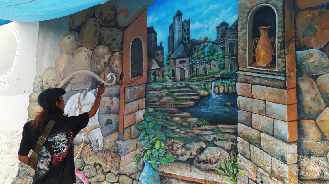 Makin Cantik, Kampung Bantaran Sungai Kayutangan Heritage Dihias Mural 3D 1 Adyanos, seniman mural Kota Malang tengah menyelesaikan lukisan mural berikon kuda di kawasan bantaran sungai Kayutangan Heritage. (Foto: Azmy/Tugu Jatim)