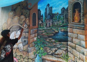 Adyanos, seniman mural Kota Malang tengah menyelesaikan lukisan mural berikon kuda di kawasan bantaran sungai Kayutangan Heritage. (Foto: Azmy/Tugu Jatim)