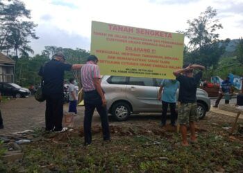 Saat pemasangan papan pengumuman tanah sengketa oleh para customer Perumahan Grand Emerald Malang. (Foto:Rap/Tugu Jatim)