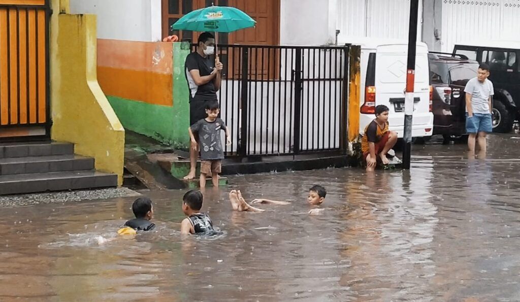 Anak-anak memanfaatkan banjir di kawasan Jalan Kedawung, Kota Malang untuk berenang gratis, Minggu (14/3/2021). (Foto : Azmy/Tugu Malang/Tugu Jatim)