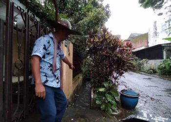 Warga menunjukkan lokasi temuan hewan diduga buaya yang sedang melintas di parit perumahan warga. (Foto : Azmy/Tugu Malang/Tugu Jatim)