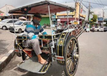 Suprapto duduk di delmannya sambil menunggu penumpang di Alun-Alun Batu. (Foto: Sholeh/Tugu Jatim)