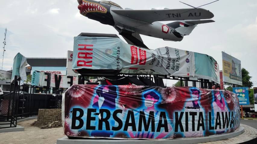Monumen Pesawat di Jalan Seokarno Hatta, Kota Malang yang dipenuhi papan reklame dan akhirnya ditutup oleh spanduk. (Foto: Feni Yusnia/Tugu Malang/Tugu Jatim)