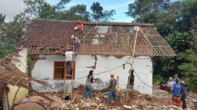 Warga bergotong-royong mengamankan atap yang masih bisa difungsikan di puing-puing rumah Mujiati. (Foto: M Sholeh/Tugu Malang/Tugu Jatim)