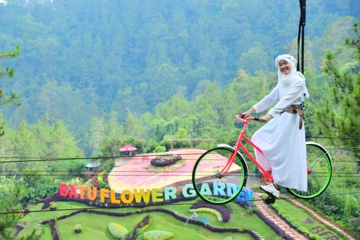 Wisatawan menikmati salah satu wahana yaitu gowes udara di Batu Flower Garden. (Foto: Batu Flower Garden/Tugu Jatim)