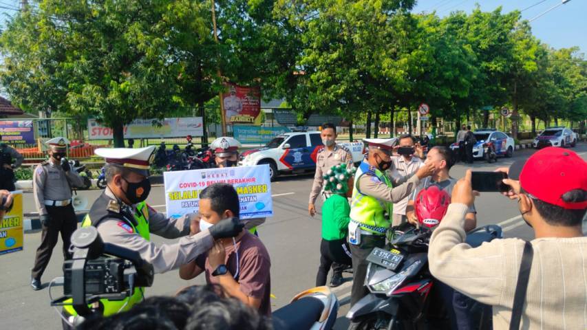 Petugas memberikan masker kepada warga. (Foto: Rochim/Tugu Jatim)