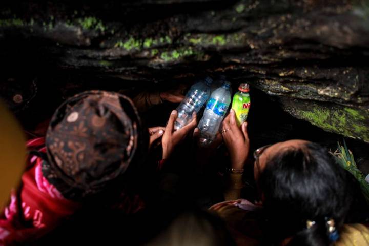 Pengambilan air suci yang mengalir di dinding gua.(Foto: Bayu Eka/Tugu Jatim)