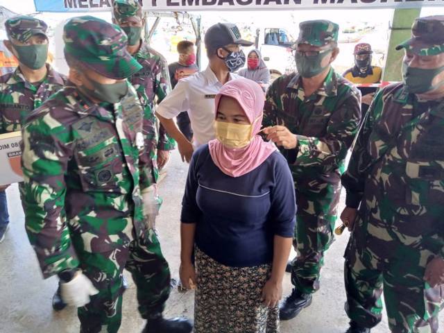 Dandim 0811 Tuban Letkol Inf Viliala Romadhon memakaikan masker kepada warga di Pasar Ikan Glondonggede, Kecamatan Tambakboyo, Tuban. (Foto: Rochim/Tugu Jatim)