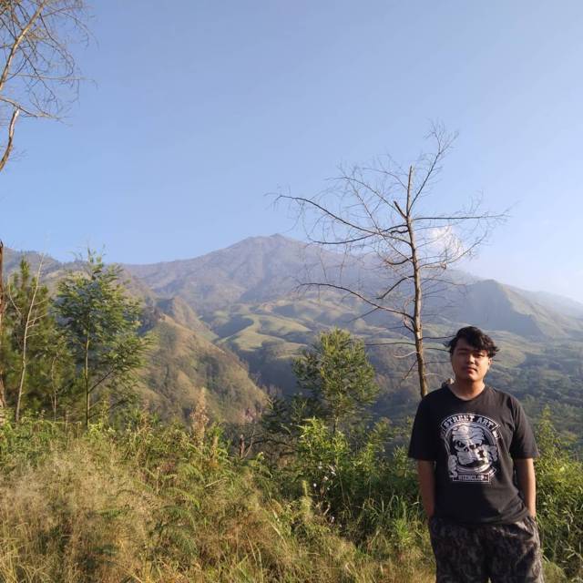 Salah satu pendaki berswafoto di Budug Asu, Malang, di belakangnya tampak keindahan pemandangan pegunungan. (Foto: Rizal Adhi/Tugu Jatim)