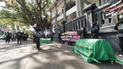 Aksi aktivis buruh migran di Malang menggotong keranda mayat di depan gedung DPRD Kota Malang, Selasa (29/6/2021) siang. Mereka menuntut penanganan kasus di BLK-LN PT CKS diusut tuntas. (Foto: M Ulul Azmy/Tugu Malang/Tugu Jatim)