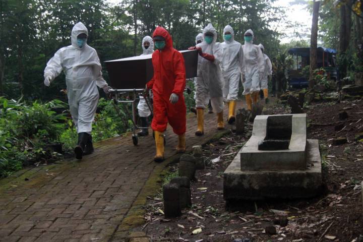 Petugas pemulasaraan jenazah Covid-19 tengah melakukan proses memakamkan pasien Covid-19 di UPT PPU Kota Malang, Kamis (24/6/2021). (Foto: Rubianto/Tugu Malang/Tugu Jatim)