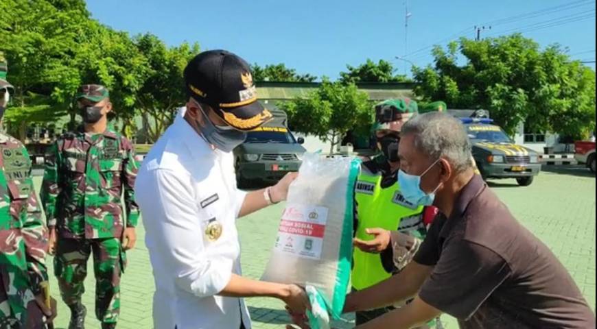 Bupati Tuban Aditya Halindra Faridzki menyerahkan bantuan beras dan masker kepada perwakilan masyarakat di Makodim 0811 Tuban. (Foto: Rochim/Tugu Jatim)