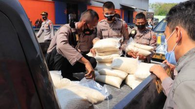 Saat anggota Polres Tuban memuat bantuan beras kemasan 5 kilogram di masing-masing mobil patroli di Kantor Gudang Bulog Tuban. Bantuan ini akan didistribusikan ke warga terdampak Covid-19 dan PPKM Darurat. (Foto: Humas Polres Tuban/Tugu Jatim)