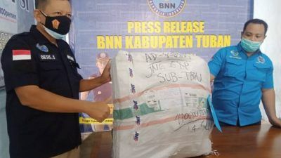 Kasi pemberantasan BNNK Tuban, Kompol Desis Susilo saat memperlihatkan bungkusan paket ekspedisi yang digunakan pengiriman narkotika jenis ganja yang ditujukan ke alamat pelaku, dengan manyatut nama anaknya. (Foto: Moch Abdurrochim/Tugu Jatim)