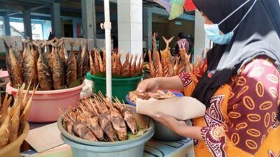 Salah satu pedagang ikan asap, Maimuma yang sedang melayani pembeli barang dagannya di Plaza Ikan Tuban. (Foto: Moch Abdurrochim/Tugu Jatim)