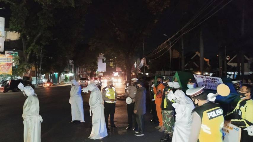 Petugas gabungan di Kota Malang saat sosialisasi bahaya Covid-19 selama masa PPKM Darurat menggunakan keranda mayat dan sosok pocong, Senin (5/7/2021) malam. (Foto: M Ulul Azmy/Tugu Malang/Tugu Jatim)