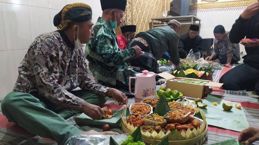 Warga makan bersama usai menggelar selamatan tolak bala pada Kamis Legi (08/07/2021). (Foto:Azmy/Tugu Jatim)