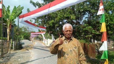 Slamet, Ketua RT Dusun Gumelem, Desa Bogangin, Kecamatan Sumberrejo, Kabupaten Bojonegoro, saat foto berlatar belakang pembentangan bendera Merah Putih sepanjang 500 meter pada Selasa (10/08/2021). (Mila Arinda/Tugu Jatim)