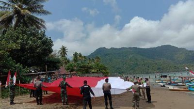 Polres Trenggalek melaksanakan apel pembentangan bendera Merah Putih raksasa sepanjang 76 meter di bibir Pantai Prigi Watulimo, Trenggalek, Senin (09/08/2021). (Foto: M. Zamzuri/Tugu Jatim)