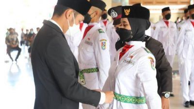 Bupati Tuban Aditya Halindra Faridzky saat menalikan kendit kepada anggota Paskibraka, yaitu Ananda Fitra dari SMAN 2 Tuban dan Mellyna Dwi Anggraini S. dari SMAN 4 Tuban sebagai simbol telah dikukuhkan, Senin (16/08/2021), di Pendapa Kridho Manunggal Tuban. (Foto: Diskominfo Tuban/Tugu Jatim)