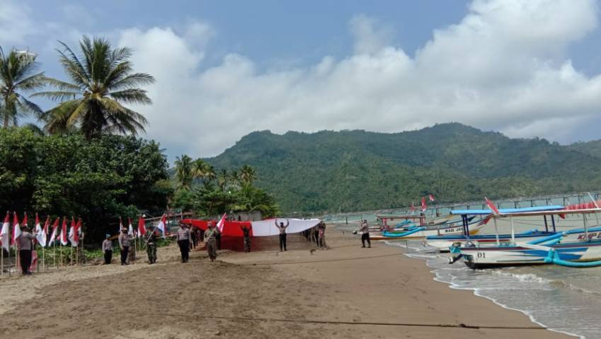 Apel pembentangan bendera Merah Putih raksasa sepanjang 76 meter dilakukan di bibir Pantai Prigi Watulimo, Trenggalek, Senin (09/08/2021). (Foto: M. Zamzuri/Tugu Jatim)